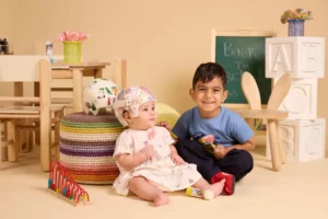 פלג בן ה-3 וריף בת ה-8 חודשים יושבים על סט צילומים. ריף חובשת קסדה רפואית לאחר ניתוח קרניוסינוסטוזיס במרכז שניידר.