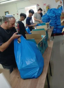 תלמידים מכפר הנוער אמית עליה פתח תקווה אורזים סלי מזון לנזקקים בעמותת חסדי יעקב.