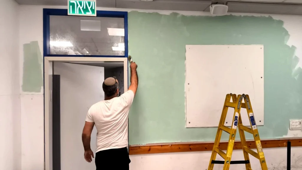 מחנך צובע קיר בכיתה בבית החינוך אמית בר אילן פתח תקווה