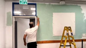 מחנך צובע קיר בכיתה בבית החינוך אמית בר אילן פתח תקווה