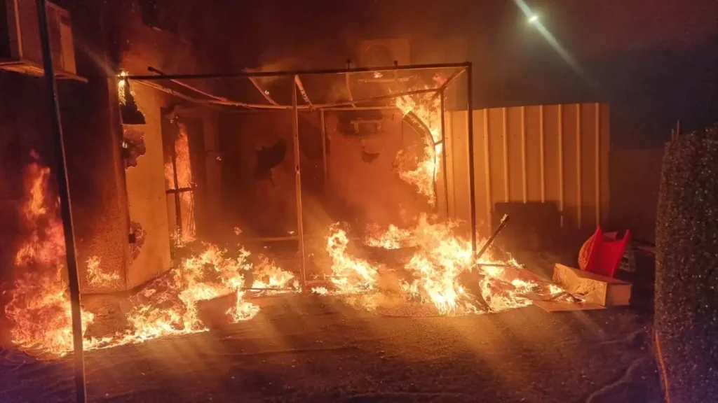 דליקה לילית של סוכה מוארת באש בוערת, הממחישה את סכנות האש בחג הסוכות.