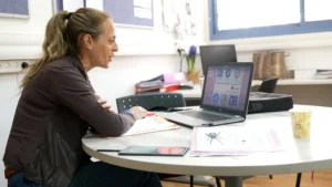 מיכל אוחנה, מורה מצטיינת מבית הספר אהוד מנור, יושבת מול מחשב נייד ומסמכים.